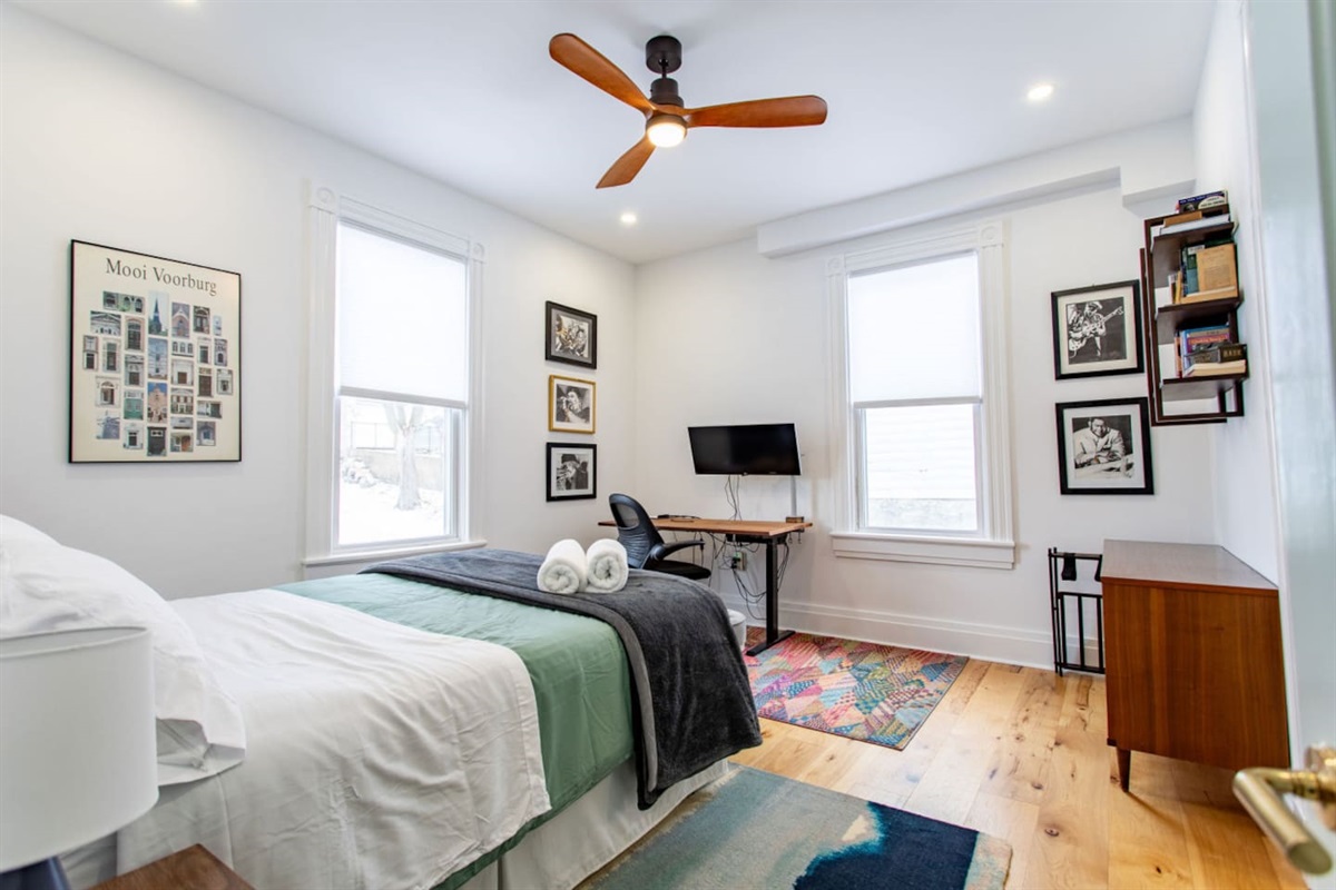A bedroom highlighting a comfortable bed, a dedicated workspace with a sleek desk, and large windows that let in plenty of natural light, creating a balanced space for both rest and productivity.