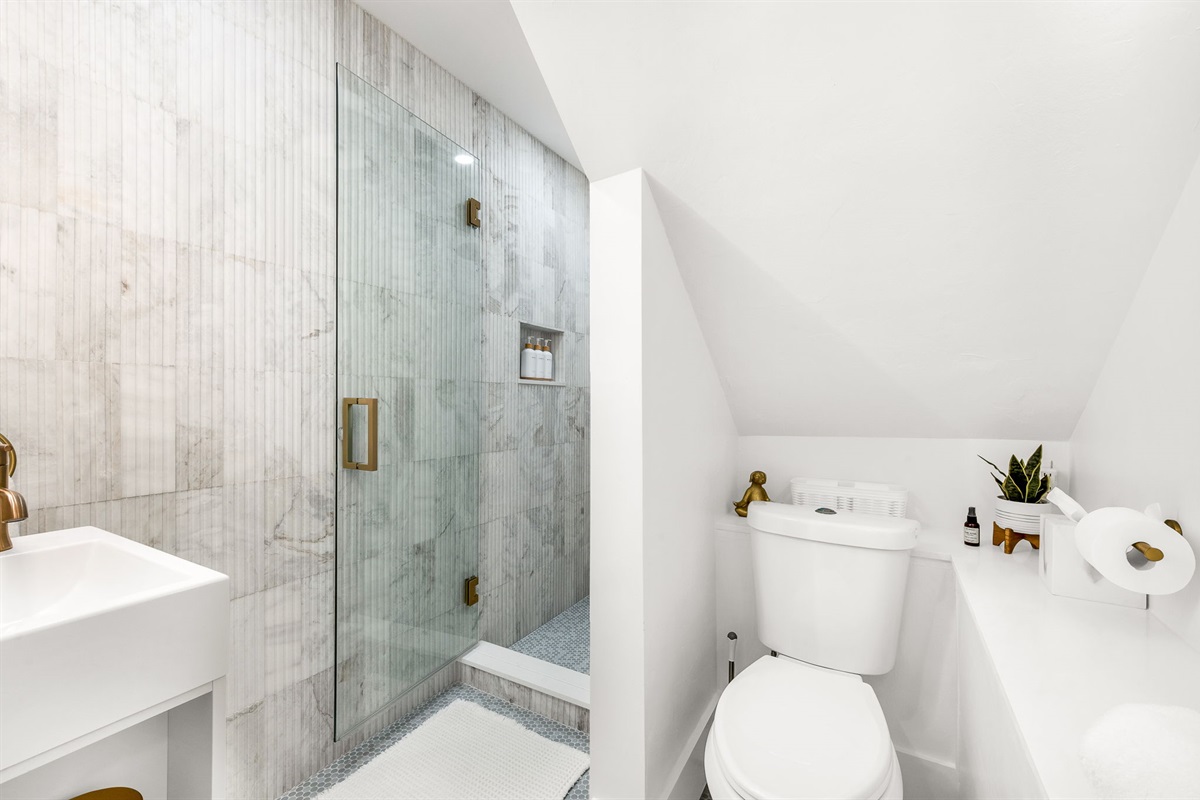 Full Bathroom #3: Discreetly located off the dining room, this newly built guest bathroom showcases floor-to-ceiling fluted marble, a spa-inspired shower, floating vanity, and an elegant make-up bar for a true resort feel.