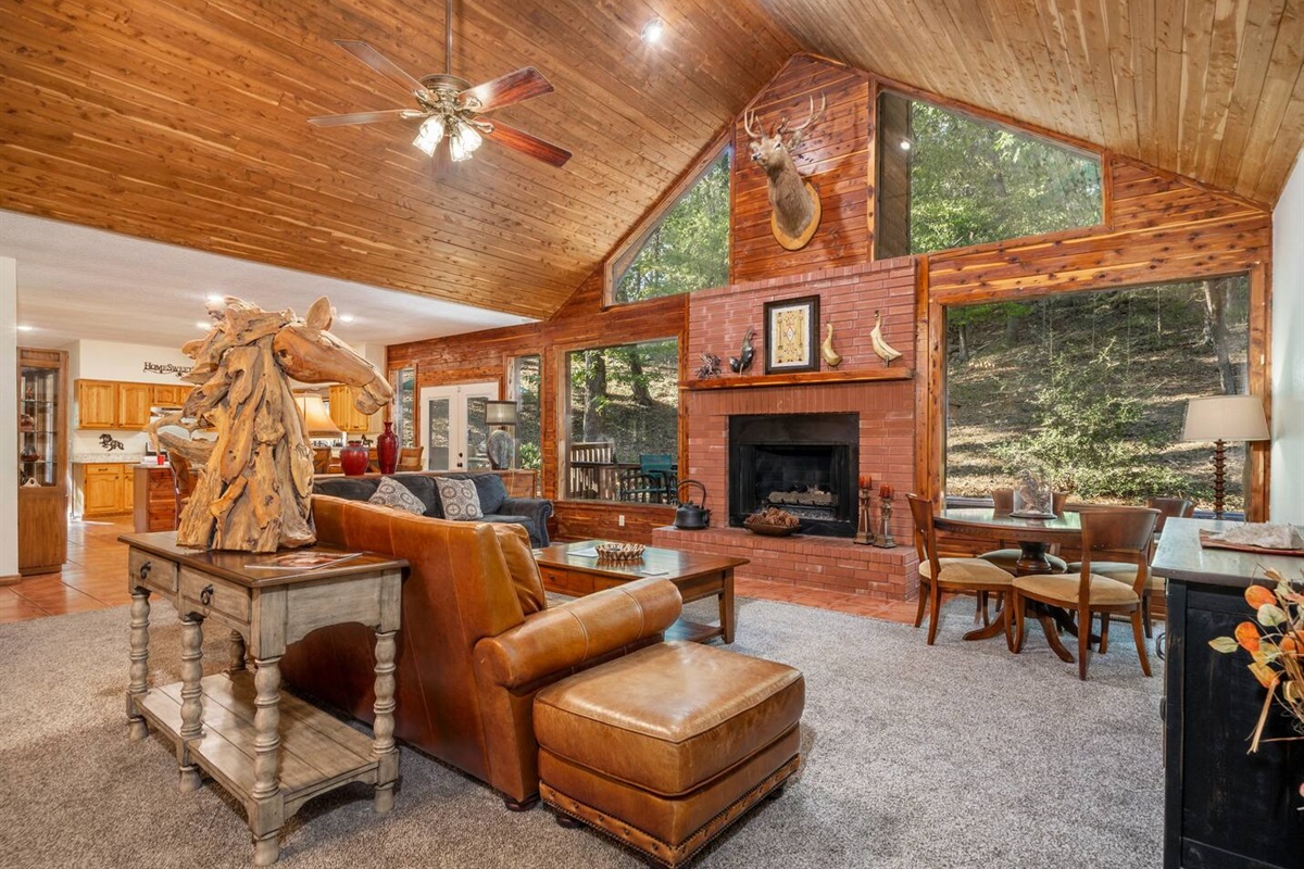 Spacious family room with vaulted ceilings, views of the woods and wildlife, gas fireplace, and plenty of room for everyone. There is a smart tv, a card/ puzzle table, leather sofas and loads of ambiance.