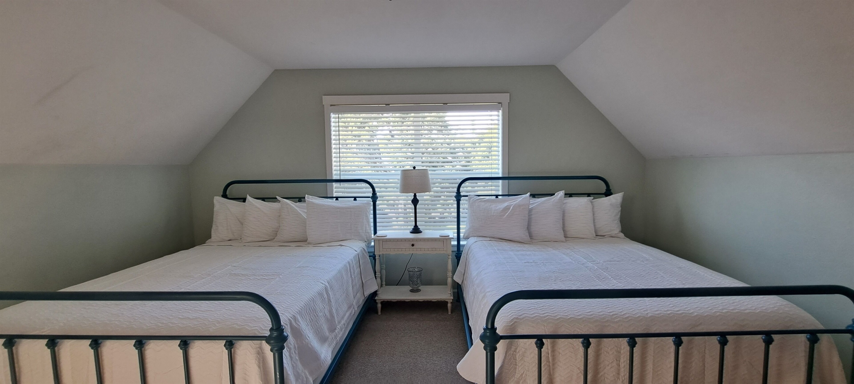 Unwind in the family suite, featuring two queen beds with luxury mattresses and sea-glass-colored walls that perfectly capture the relaxed charm of coastal living.