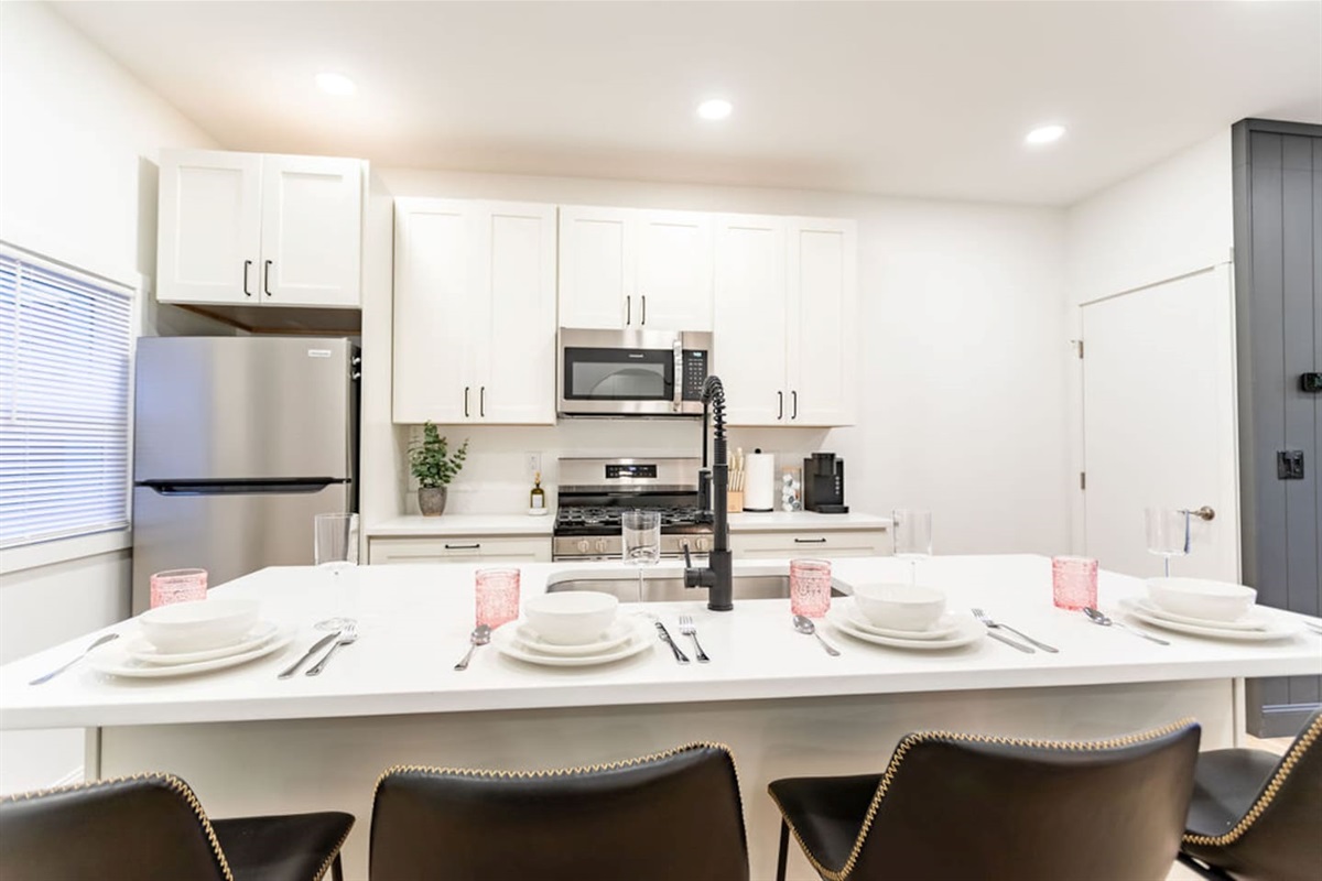 Front view of the kitchen with a sleek counter and a neatly arranged set of plates for dining.
