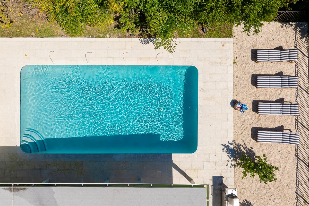 A stunning aerial view captures this luxury coastal retreat with a sparkling pool, manicured lawns, and lush tropical landscaping - offering the perfect blend of privacy, sophistication, and resort-style living just minutes from the beach.