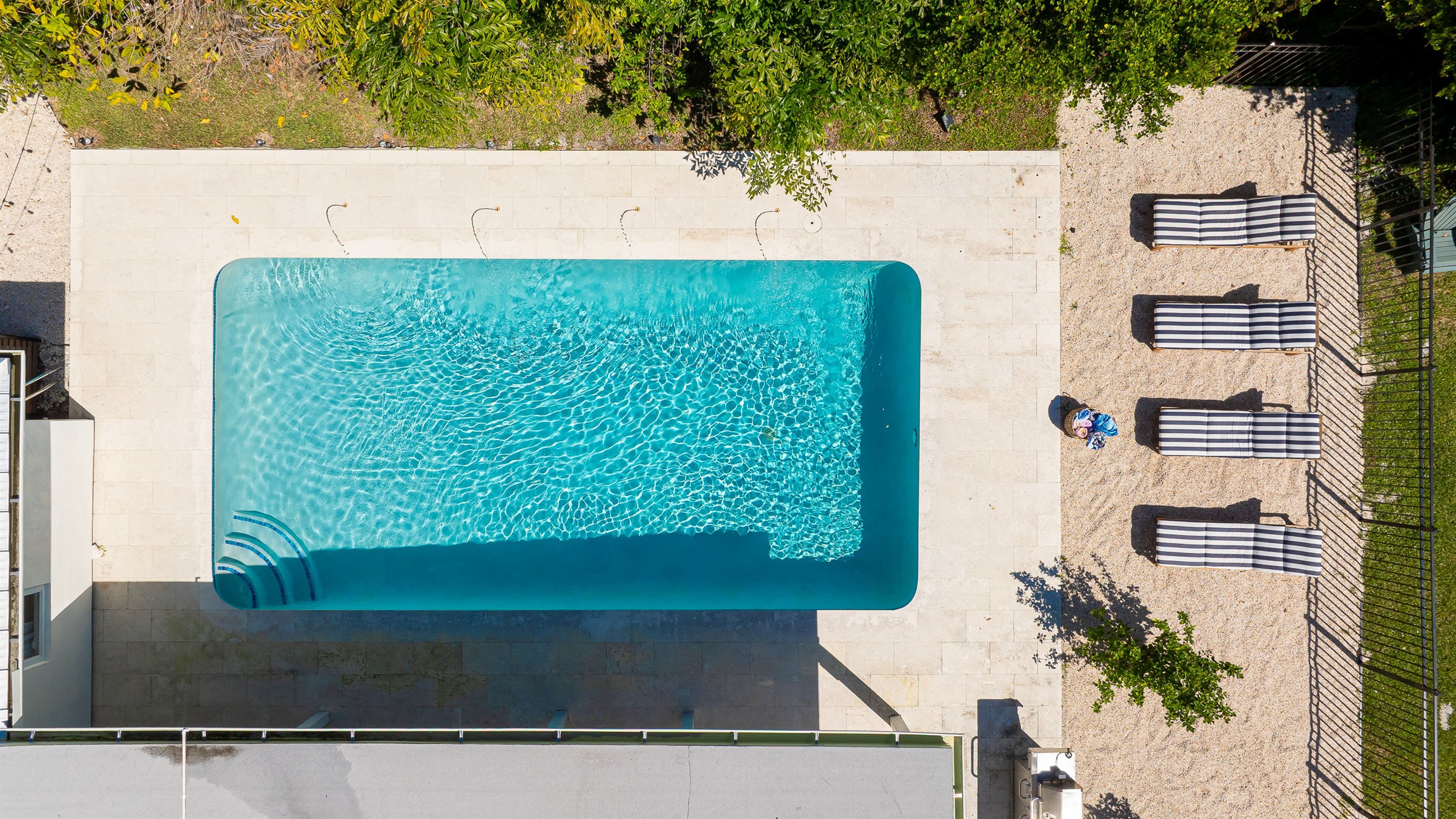 A stunning aerial view captures this luxury coastal retreat with a sparkling pool, manicured lawns, and lush tropical landscaping - offering the perfect blend of privacy, sophistication, and resort-style living just minutes from the beach.