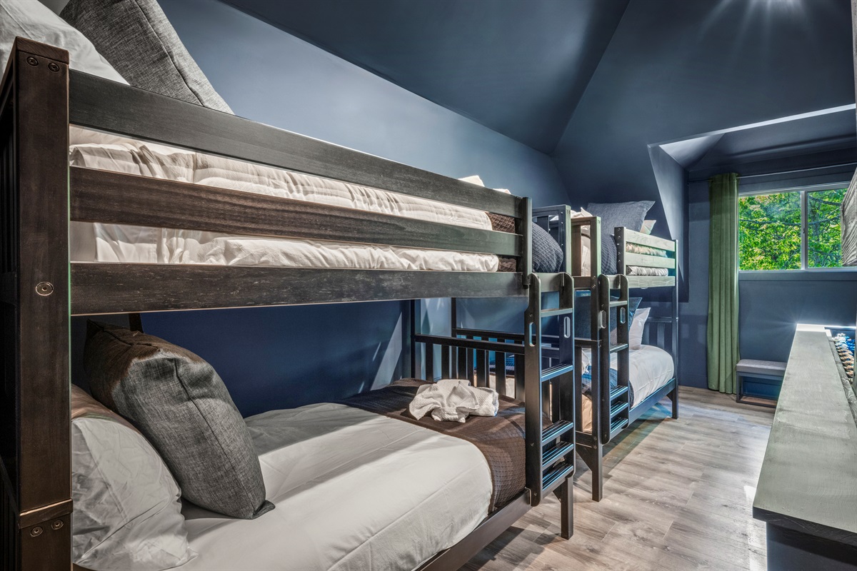 Tucked beneath vaulted ceilings, this cozy bunk room features two twin-over-twin bunks, a Smart TV, and space to play or wind down after a big day in the mountains.