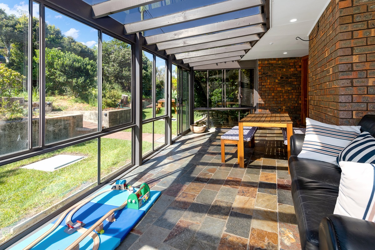 The sunroom gives the home another sitting area, with garden-facing windows, tiled floors and a play space near the front access.