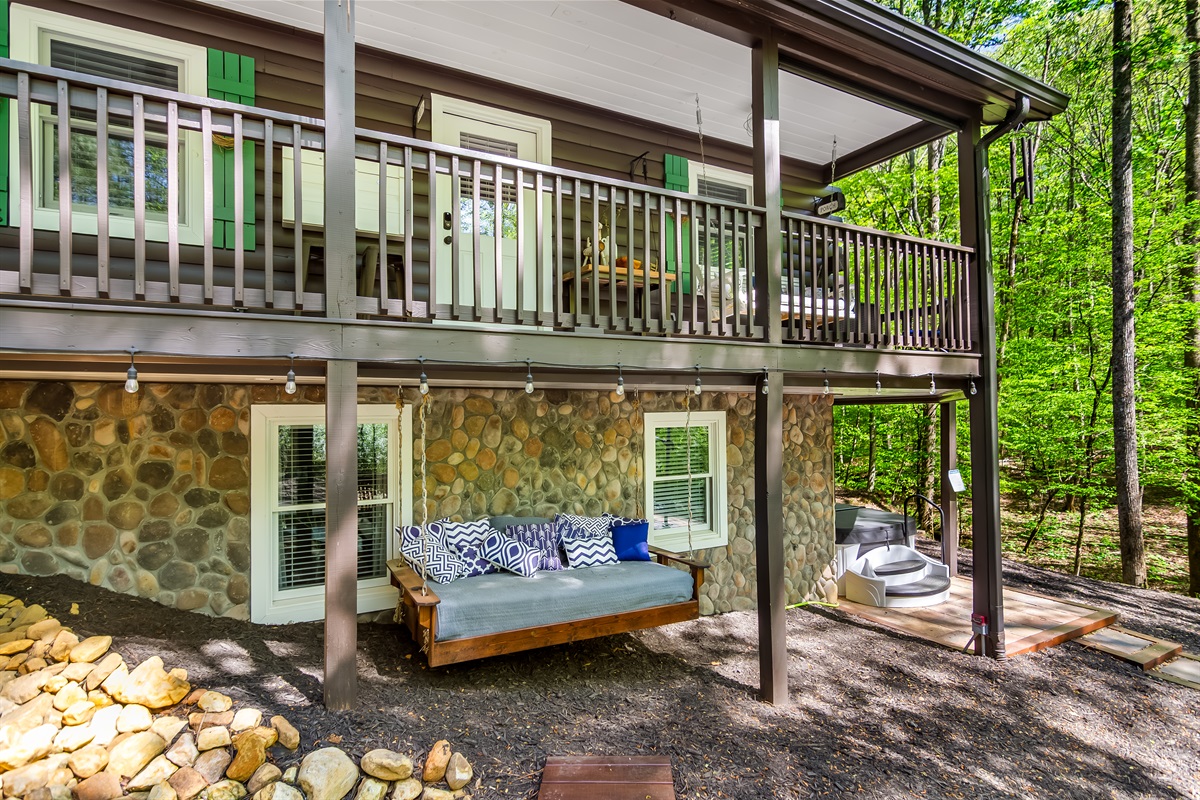 Exterior all facing the stream and hot tub below with underdecking and dimmable lights & bistro lights. A bed swing with a full deck above, with a porch swing and dining area as well.