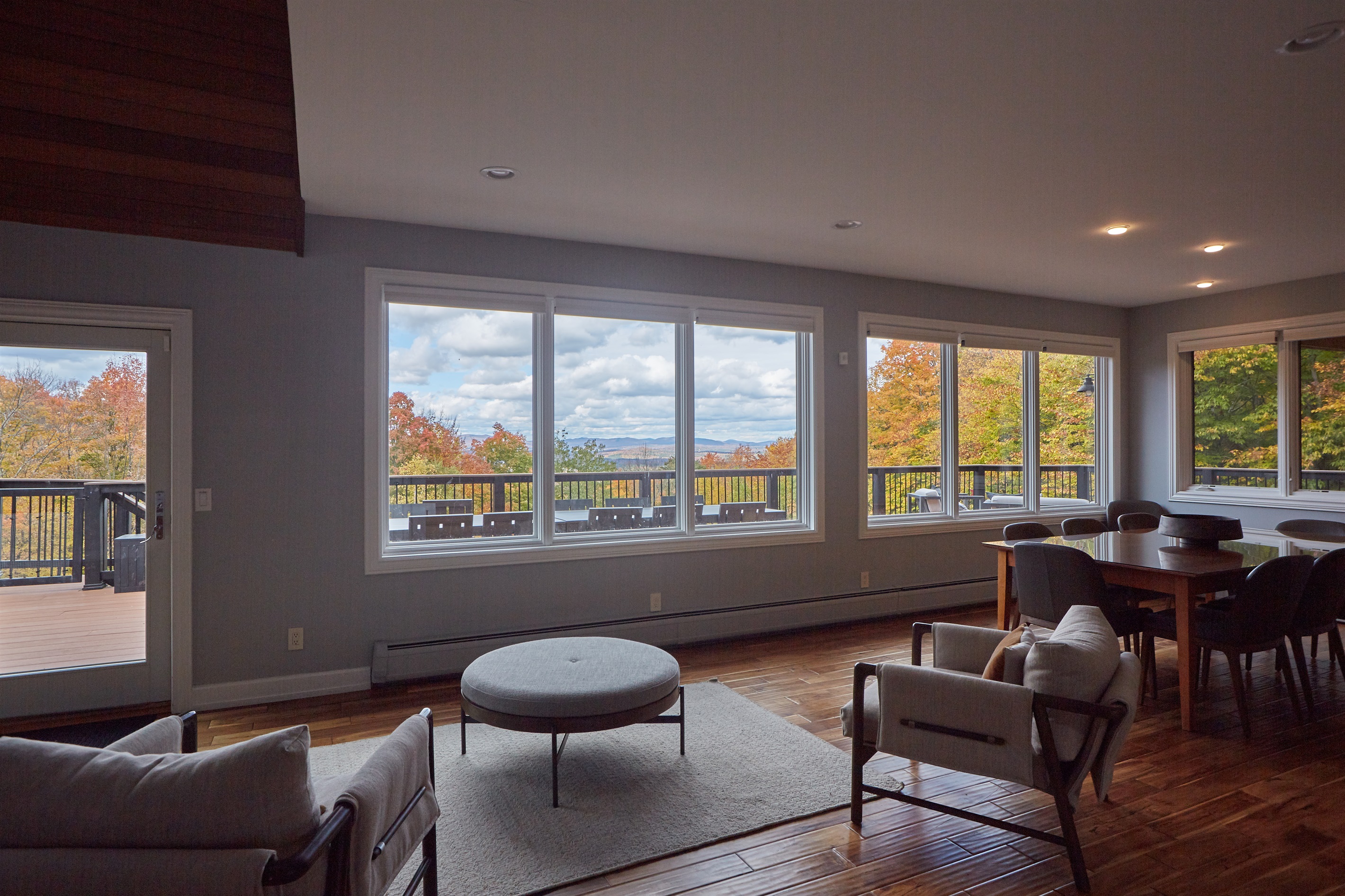 The expansive open-concept living space is flooded with natural light and features walls of windows showcasing the breathtaking surrounding scenery.