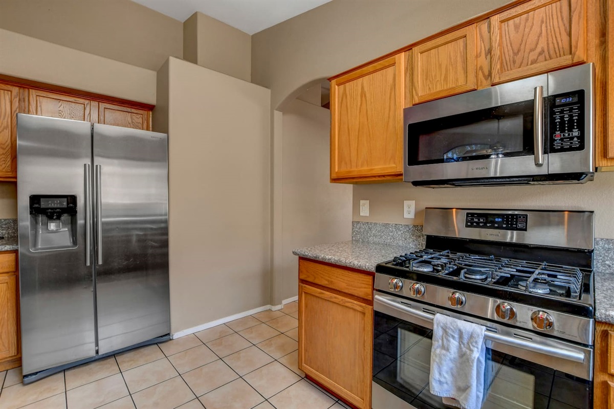 Bright kitchen with stainless appliances, gas range, and granite counters