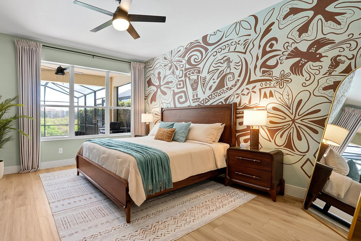 Moana King Suite: Main-floor king bedroom with a hand-painted Polynesian mural, TV and peaceful conservation views.