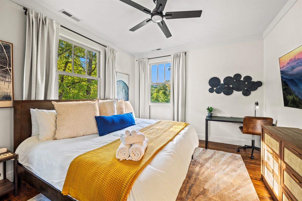 Sunlight pours into this inviting king suite, styled with soft neutrals, a pop of yellow warmth, and a welcoming desk. Rest, read, work, or just soak in the forest views.