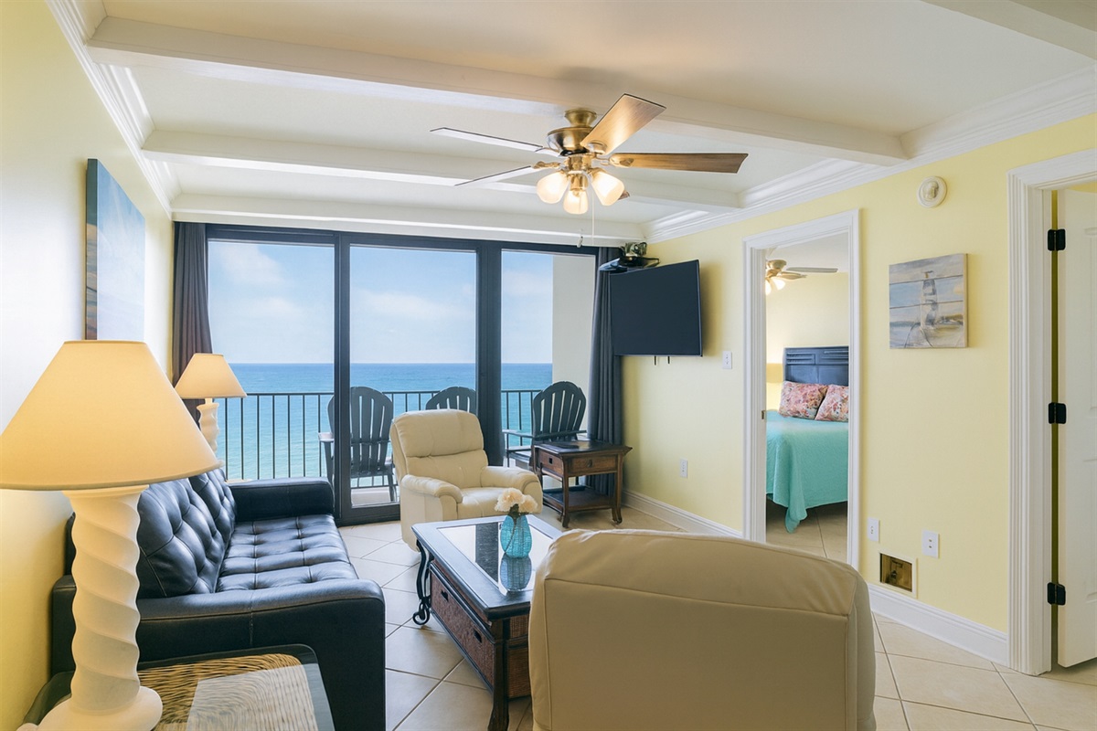 Living Room with A Great View. It Has A Queen Size Leather Sleeper Sofa, 2 Swivel/Rocker Recliners, 3 End Tables, A Coffee Table, A 58" Wall Mounted Smart TV And Balcony Access