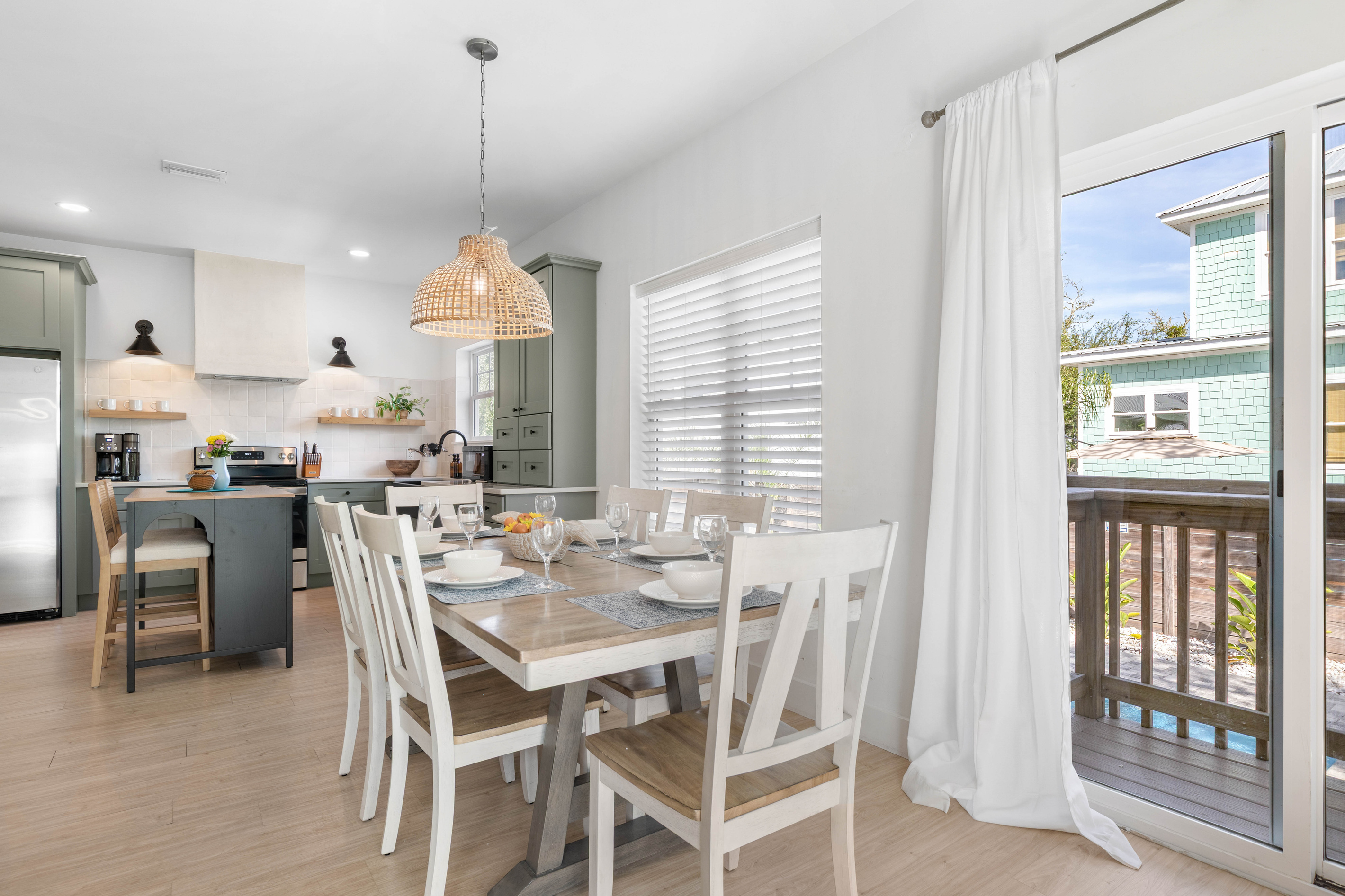 The table sits a few steps from the range, so whoever is cooking stays in the conversation. Out through the slider the pool is already in view, which is how breakfast turns into swimming most mornings here.