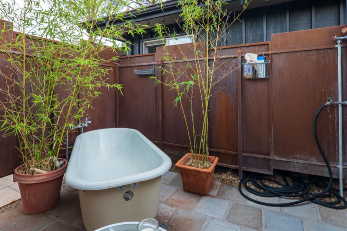 Charming outdoor soaking tub surrounded by natural wood privacy fencing and bamboo accents — a tranquil, spa-inspired escape under the open sky.