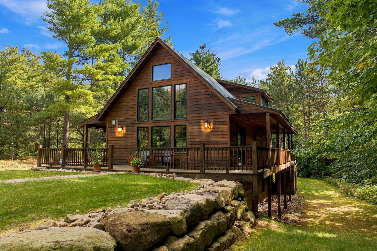 An inviting mountain retreat with expansive windows and a spacious wrap-around outdoor deck.