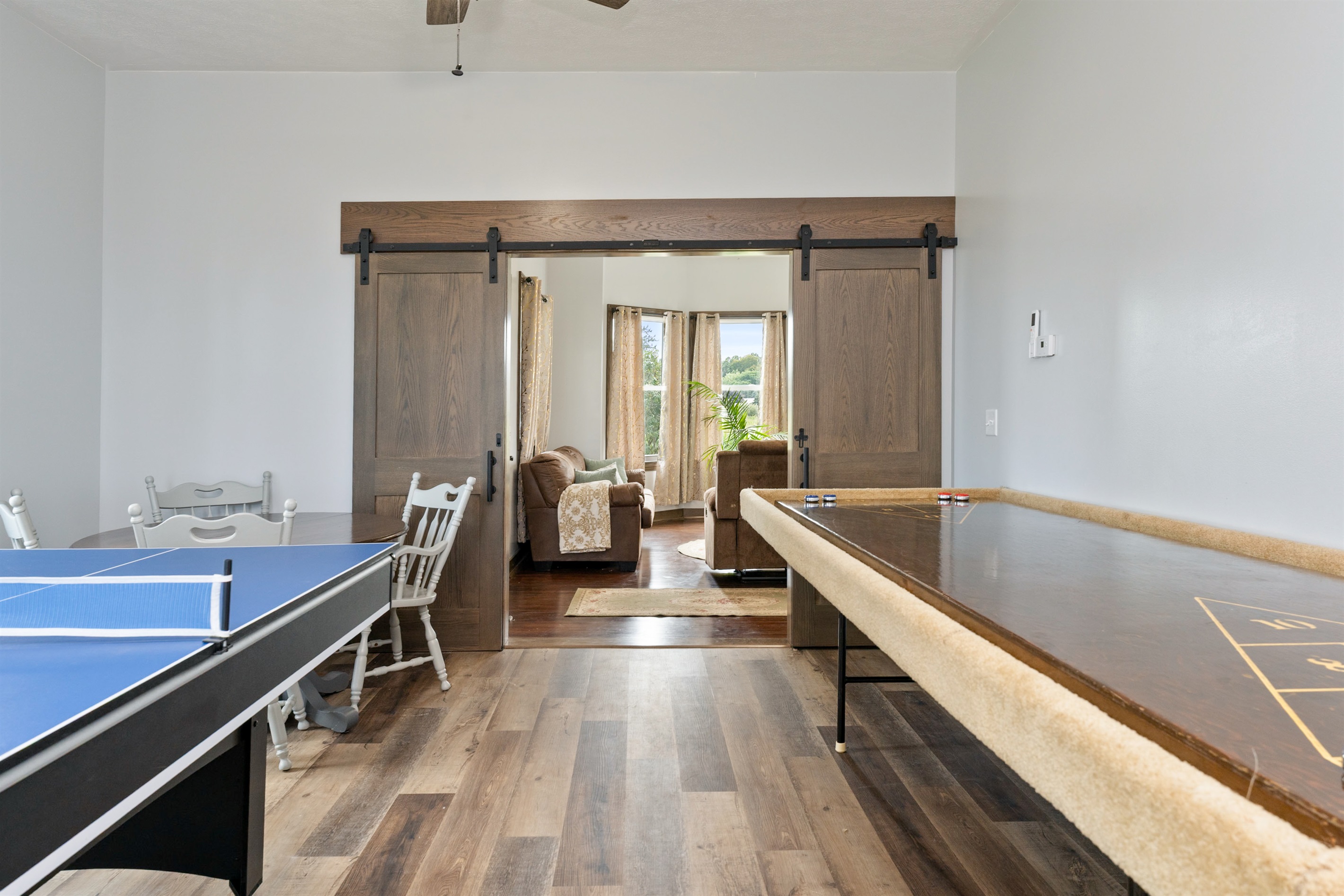Entertainment-ready game room featuring a combination ping pong/pool table, shuffleboard, and air hockey with several board games and Cornhole for outside..... endless fun!