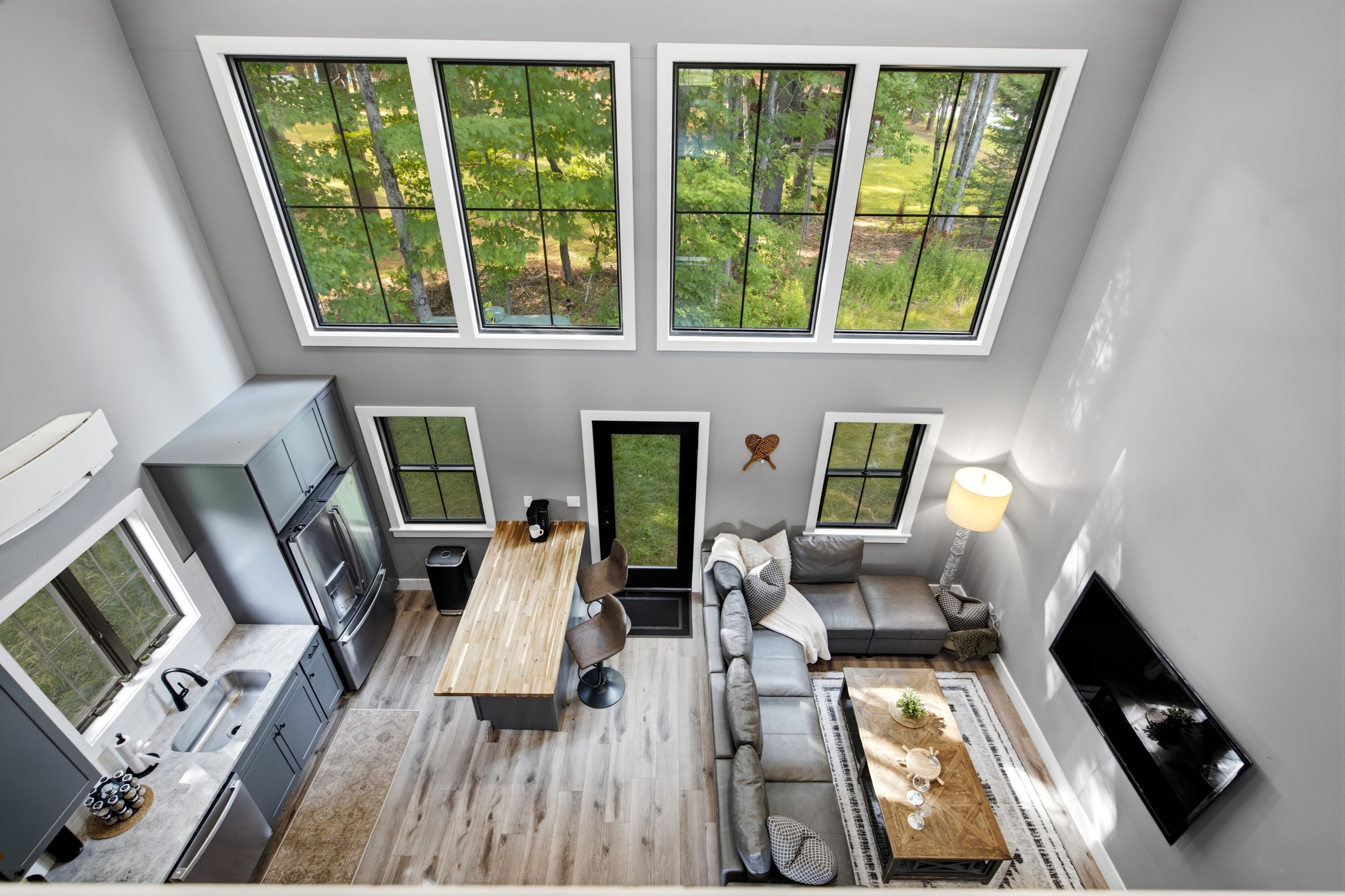 Dramatic floor-to-ceiling windows fill the open living space with natural light and beautiful wooded views.