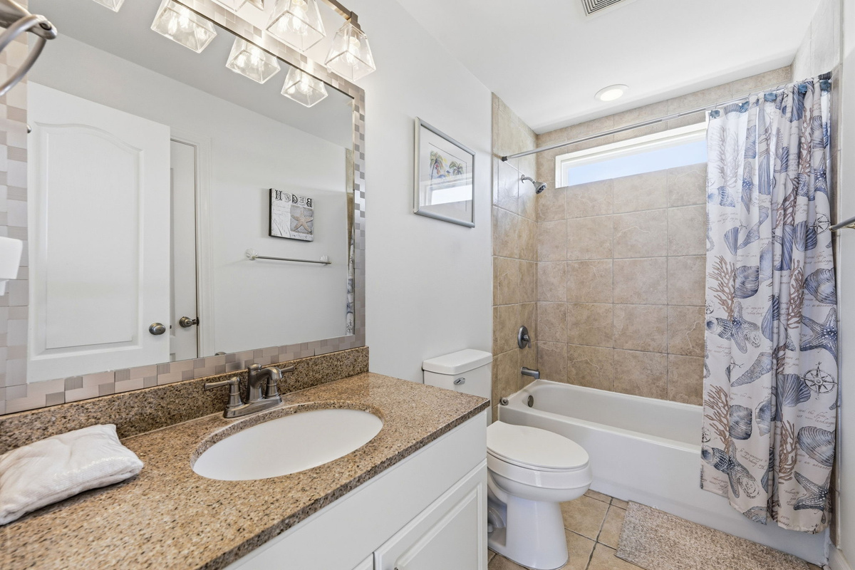 Spacious en-suite master bathroom featuring tub/shower combo, granite vanity, and coastal-inspired finishes