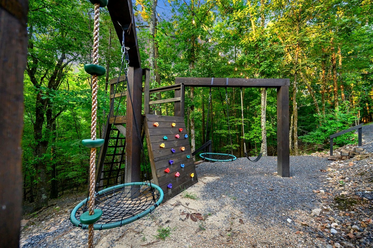 The custom play toy features a rock wall, cargo net, and four swings.  Just around the corner is a gravel path that takes you to a creek!