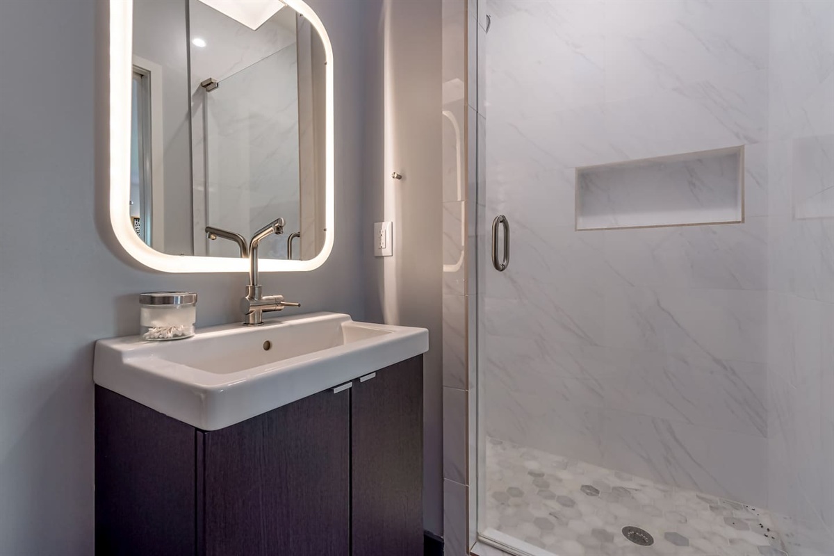 Full bath with walk in shower located in bunk room/game room and just outside bedroom with convertible chairs