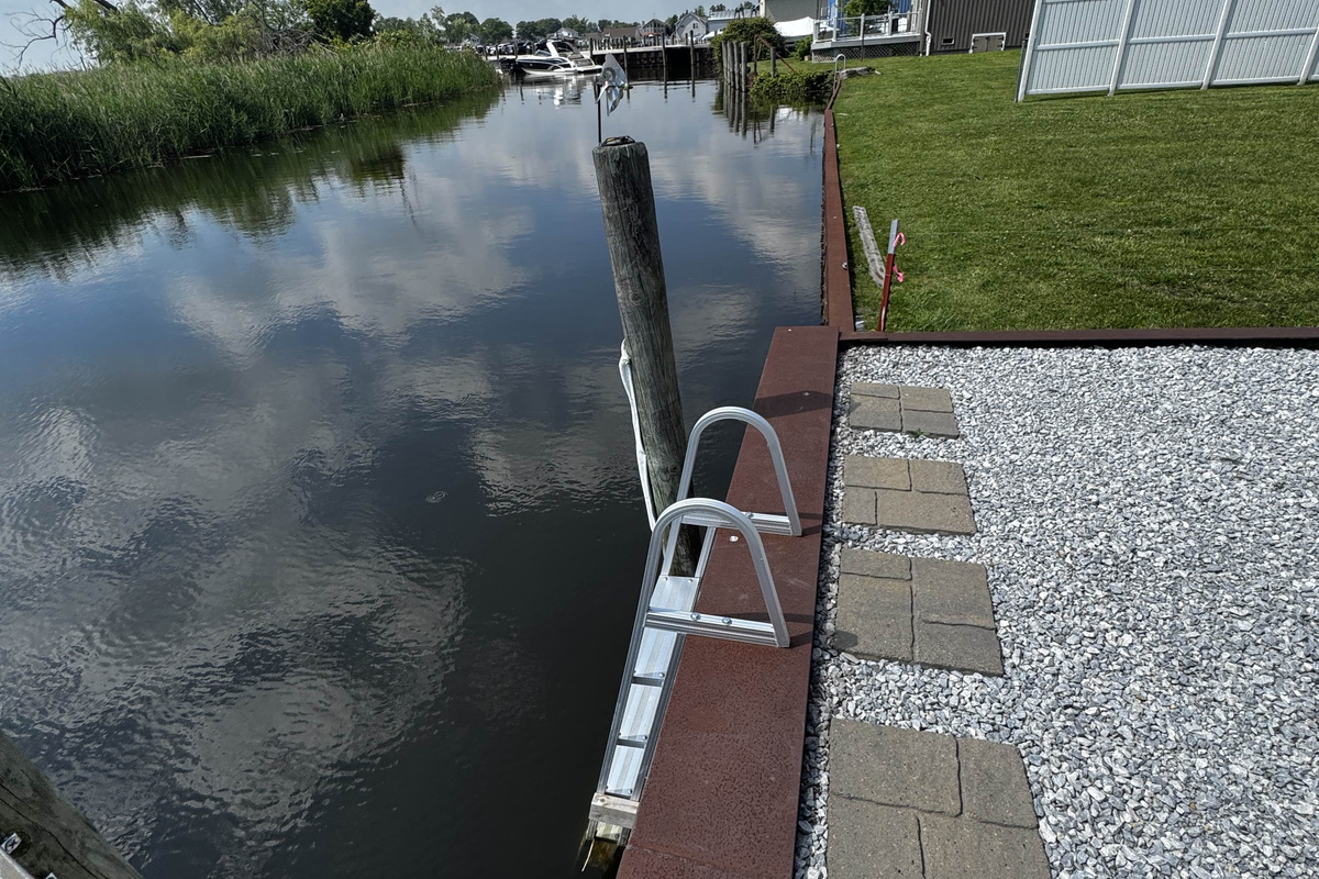 Private waterfront dock with ladder access, offering direct entry to the calm canal and peaceful water views.