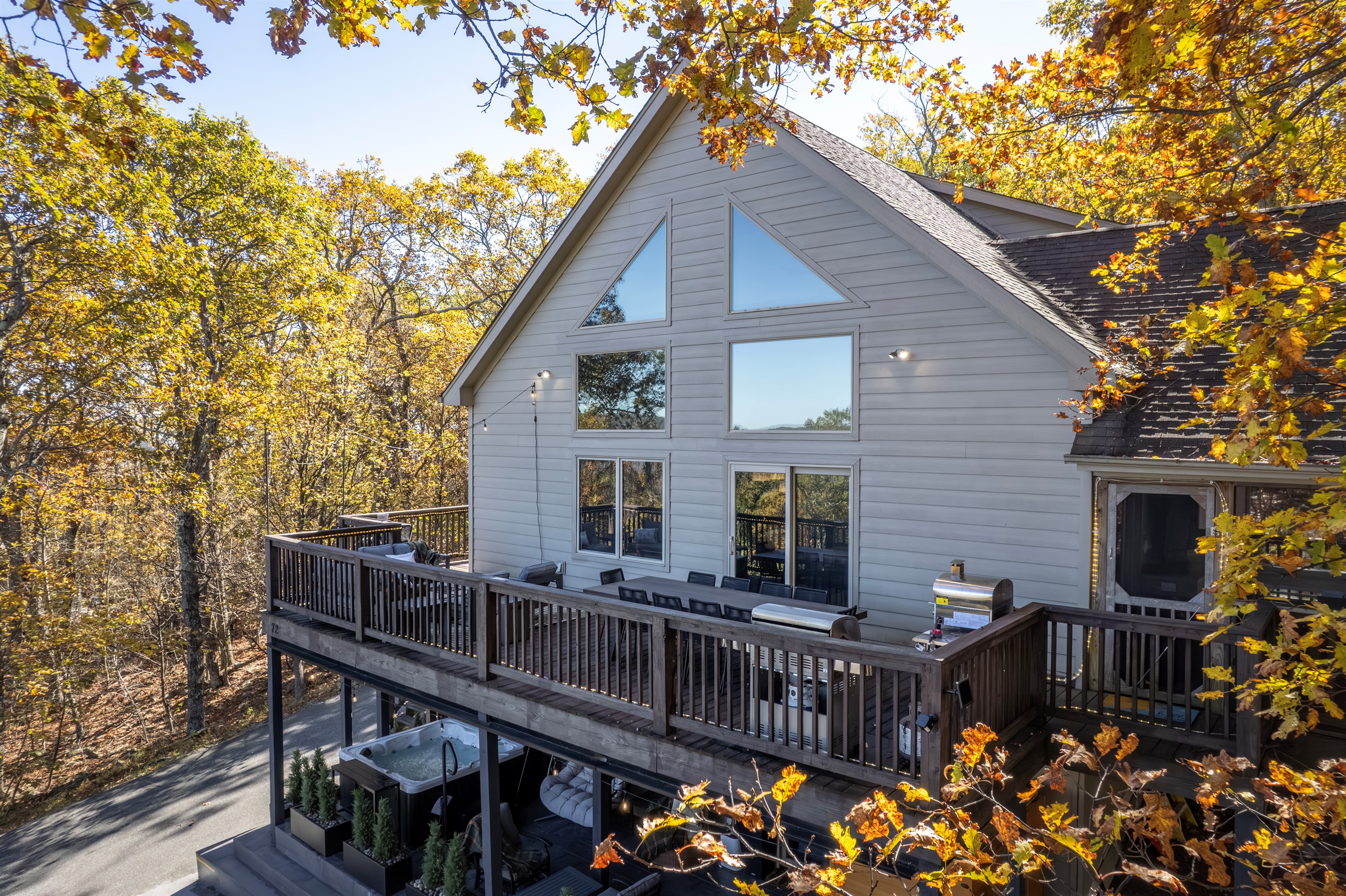 Framed by autumn leaves, the chalet’s soaring windows and wraparound deck invite gatherings in fresh mountain air and glowing seasonal light.