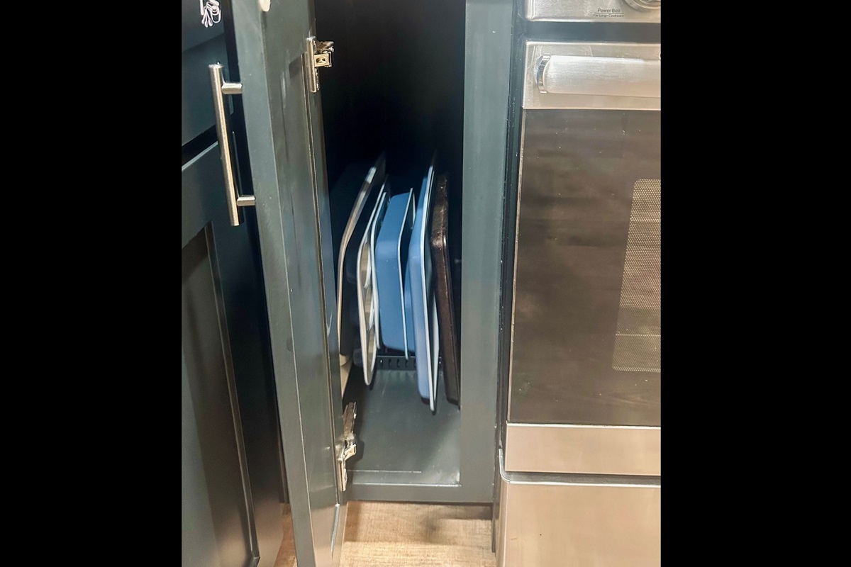 Kitchen cabinet neatly arranged with baking pans and sheets for effortless meal prep and home-style baking.