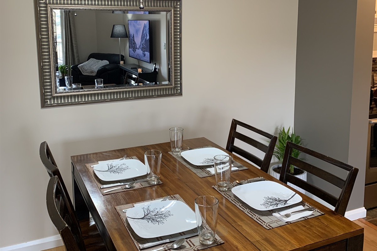 Spacious dining room with large table. Place setting for 4 guests.