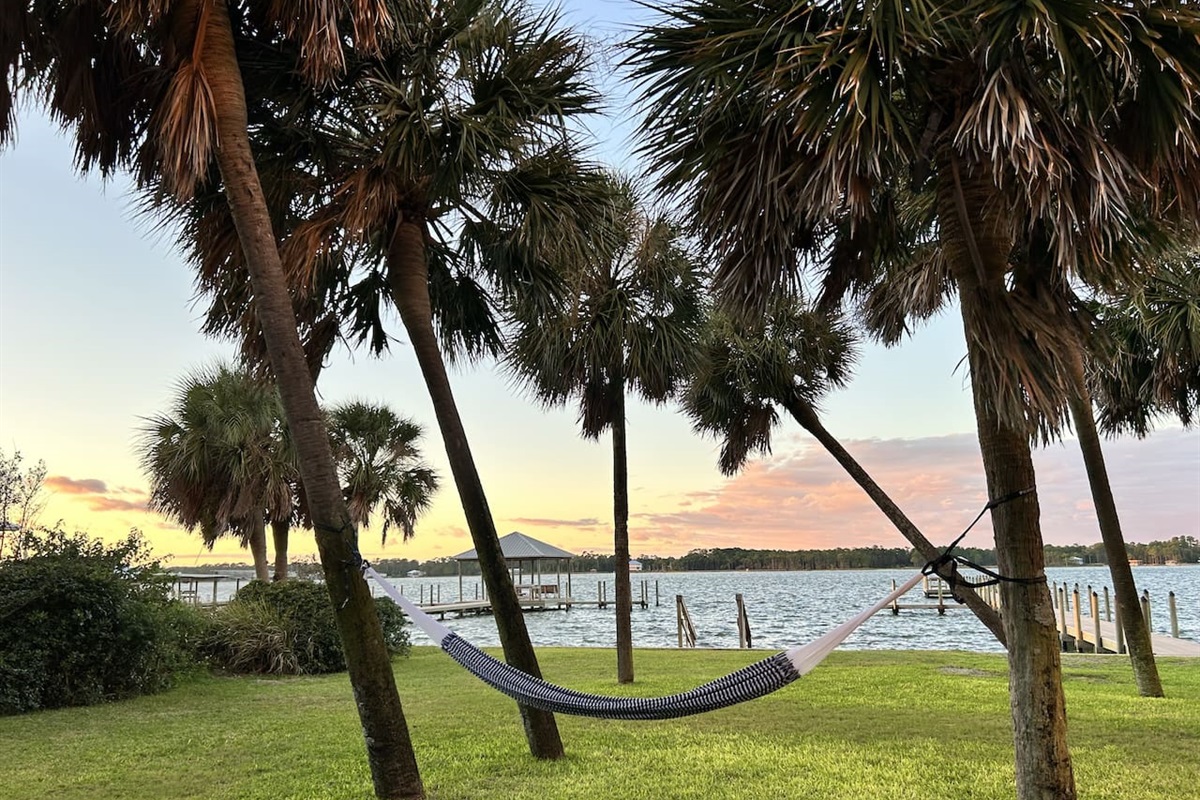 Peaceful sunset hammock retreat by the lake with palm trees and tranquil vibes.