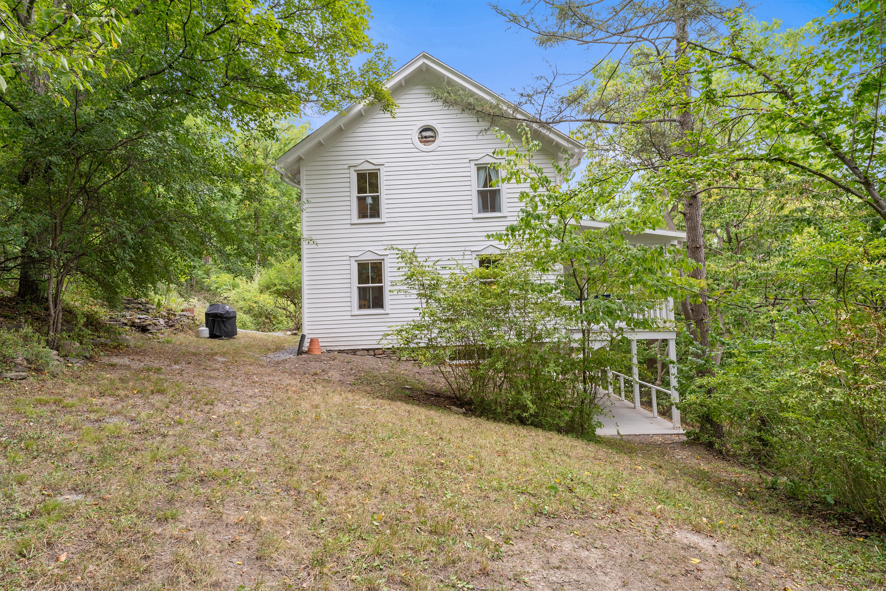 Charming white lakeside home surrounded by lush greenery, offering privacy and a serene natural setting.