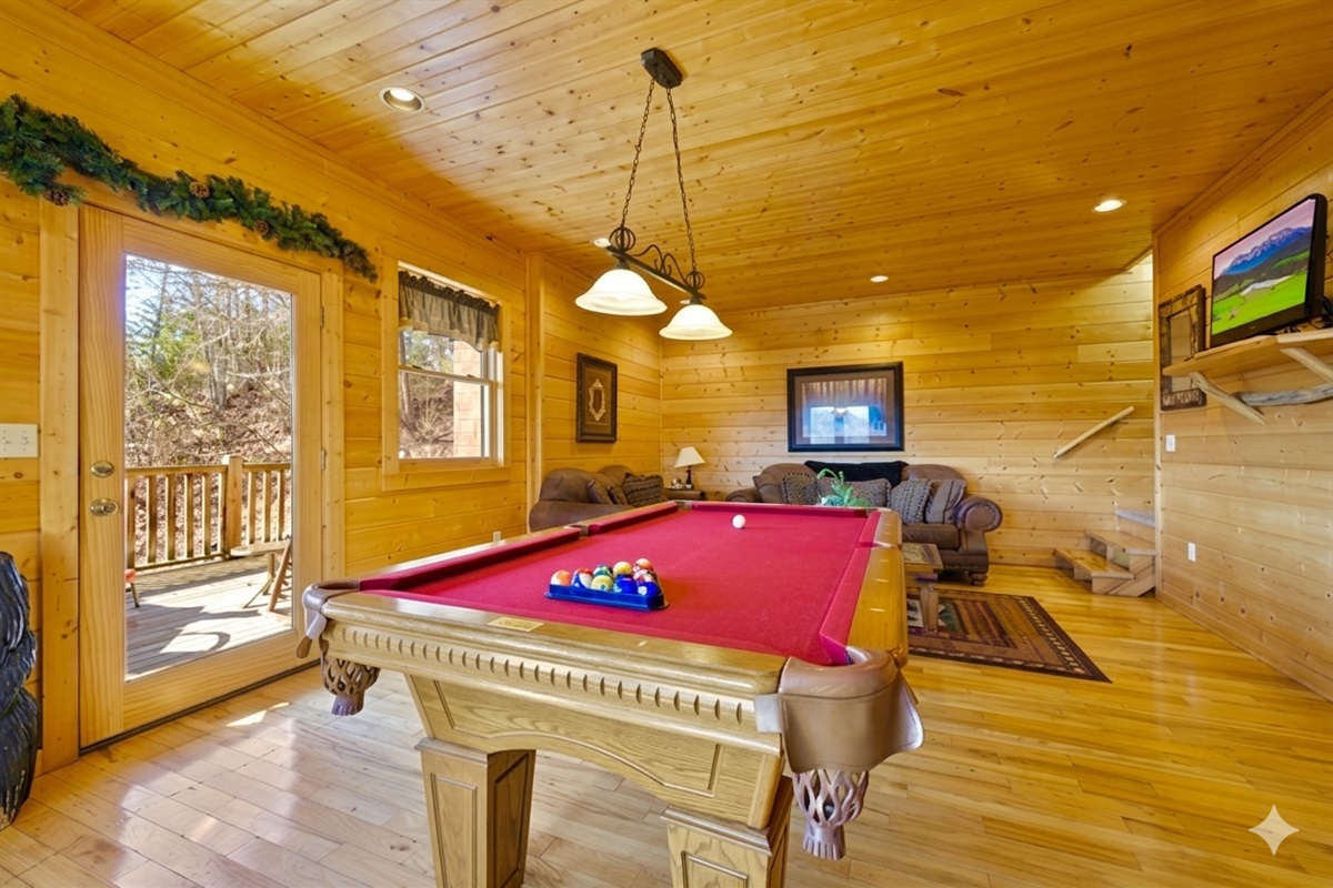 Gather for laughter and friendly matches in this cozy game room featuring a pool table, comfy seating, and TV. The warm wood interior and mountain light make it the perfect spot to unwind and connect.