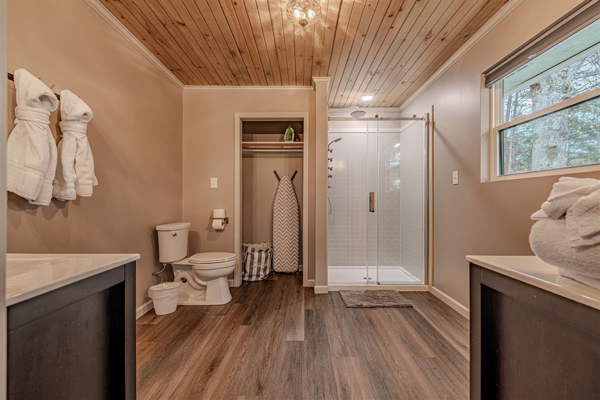 Enjoy the rustic elegance of wood-paneled ceilings paired with a bright, contemporary walk-in shower for a refreshing start.