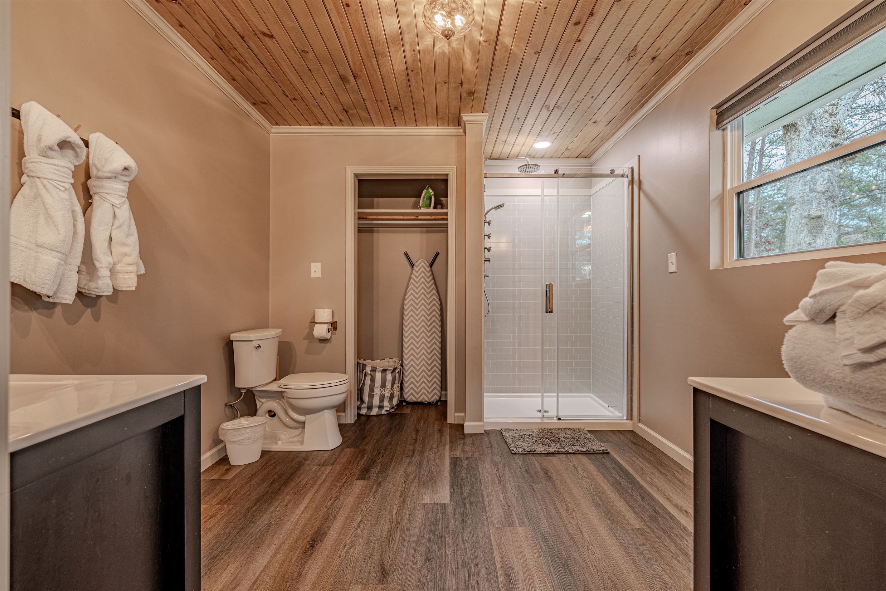 Enjoy the rustic elegance of wood-paneled ceilings paired with a bright, contemporary walk-in shower for a refreshing start.