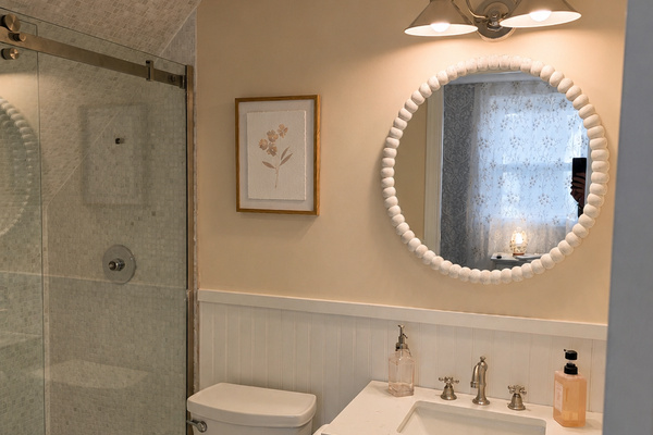 Second-floor primary bathroom with a walk-in shower, vanity area and bright mirror lighting.