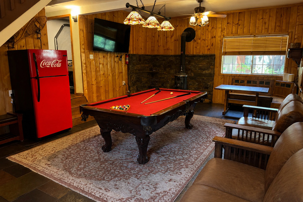 Step into the first room, featuring a pool table, smart TV, and a wood-burning fireplace. Sofas and a table provide a cozy spot to unwind and entertain.