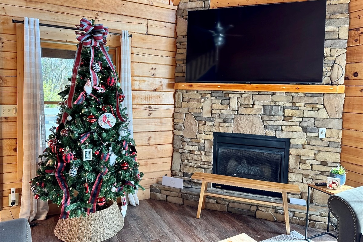 Stone fireplace, soft cabin light, and festive touches all around — the perfect holiday hideaway.