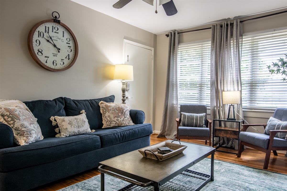 Chic and cozy sitting area, highlighted by unique accents like the oversized wall clock and plush couch pillows.