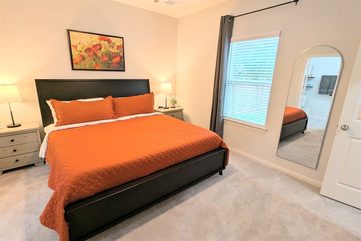 Bedroom with King bed, plush bedding, blackout curtains and en suite bathroom.