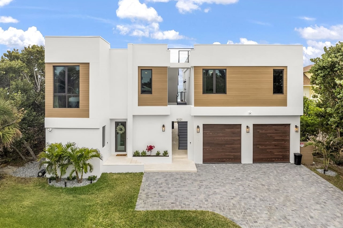 Capture the full exterior of the house with a welcoming door entrance, lush greenery and trees, convenient parking lots, sleek glass windows, and a stylish color scheme, all set on elegant flooring for a modern, inviting vibe