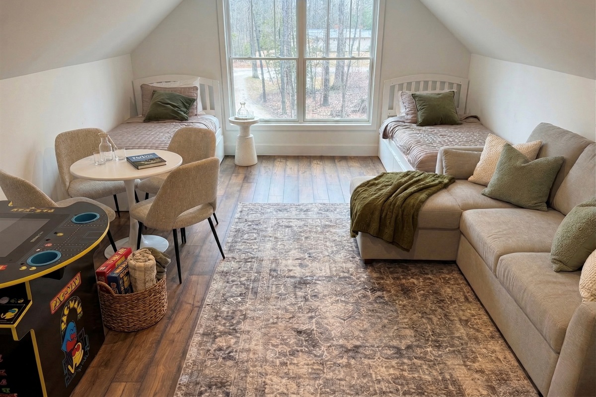 A cozy flex room with two twin beds, sleeper sofa, smart TV, Nintendo, Pac-Man arcade, and a table for board games—a fun space for all ages!