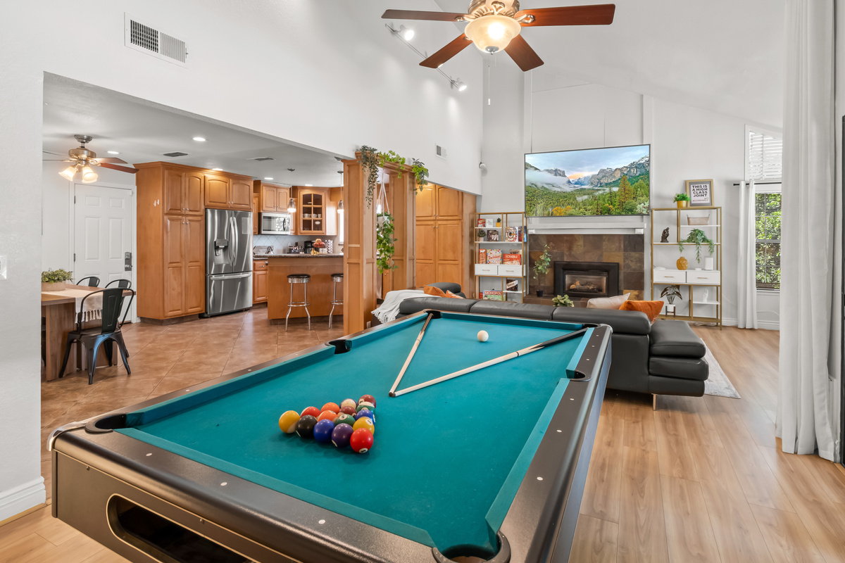 Perfect for families and groups, the open-concept main living area combines a full-size pool table, spacious lounge, fireplace, large TV, kitchen, and dining space for easy group entertainment.