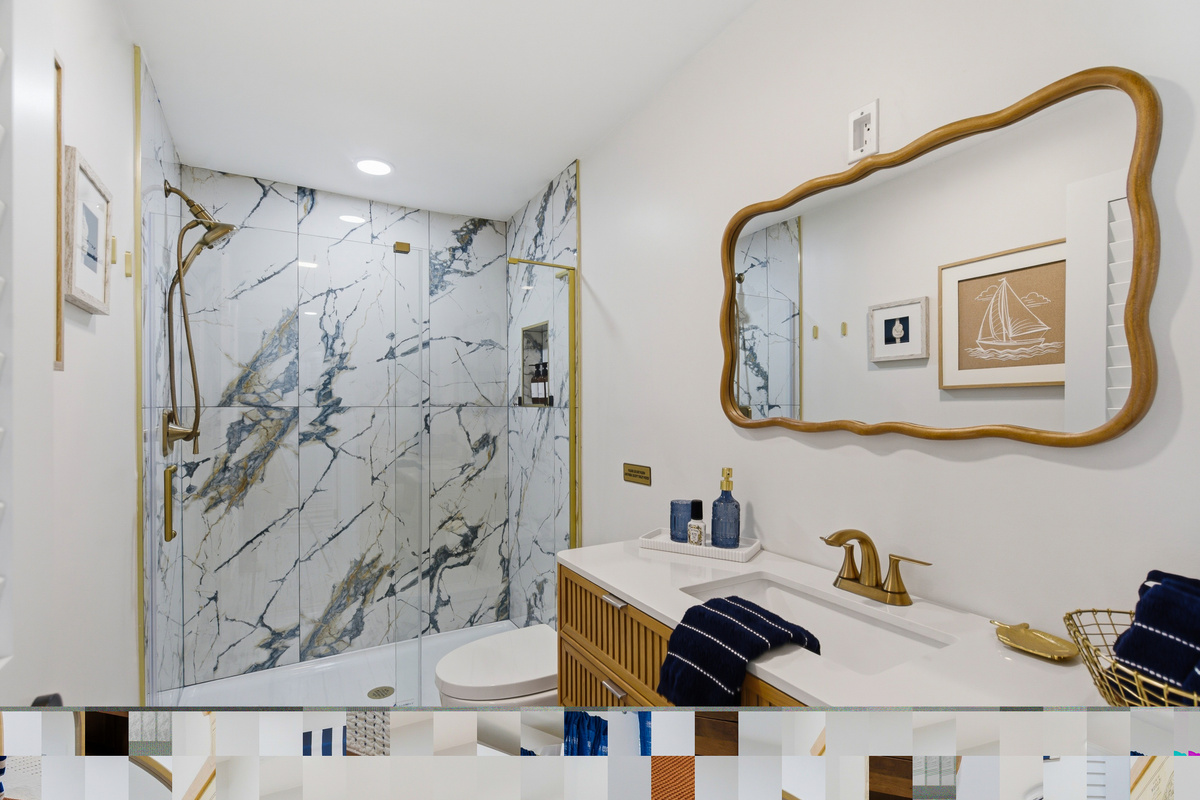 Bathroom #2 is newly remodeled with a walk in shower and marble-inspired tile, warm brass accents.