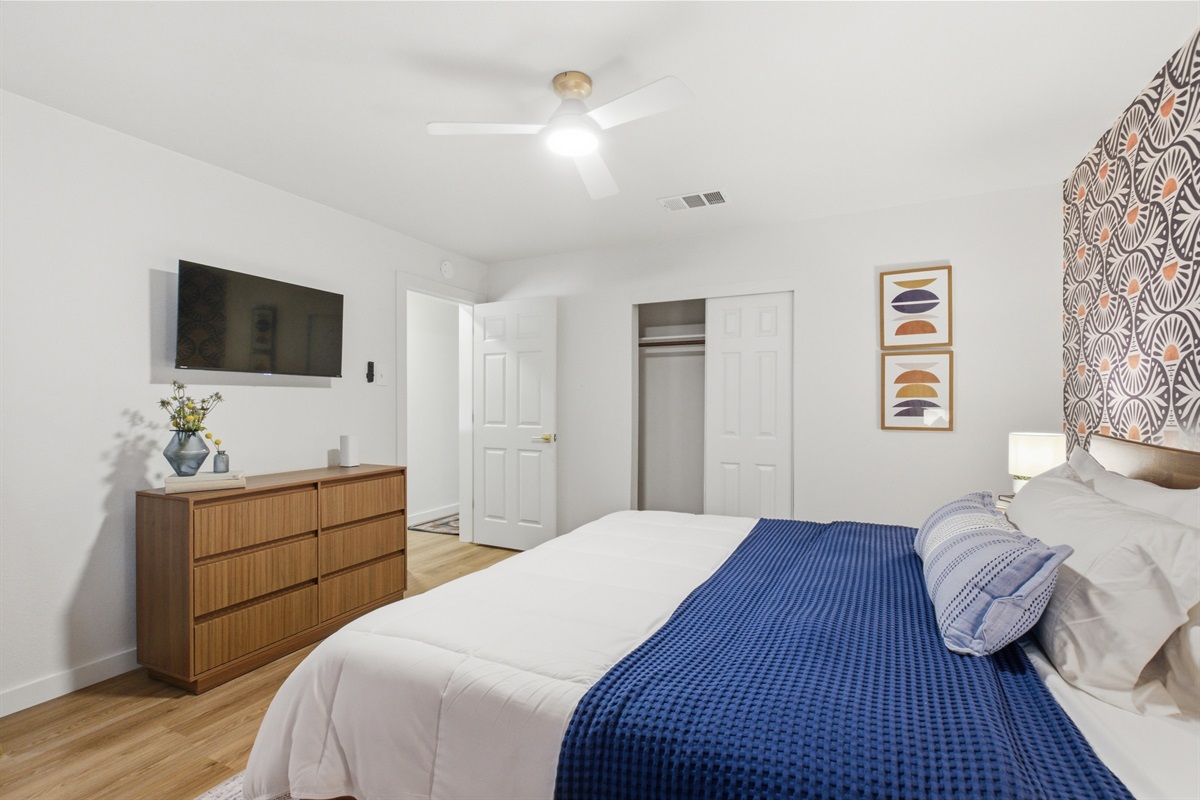 Master bedroom with dresser, Smart TV, hardwood floors, and Portable Fan. Clothing storage, hangers, and ceiling fan included. 4-bedroom Arlington vacation rental sleeps 8.