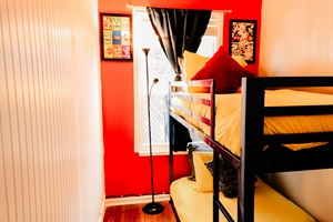 Whimsical Retreat: Twin Bunk Beds in Bold Black Frames, Sunshine Yellow Bedding, Accompanied by a Playful Super Mario Painting Against a Vibrant Red Wall 🌟🛌