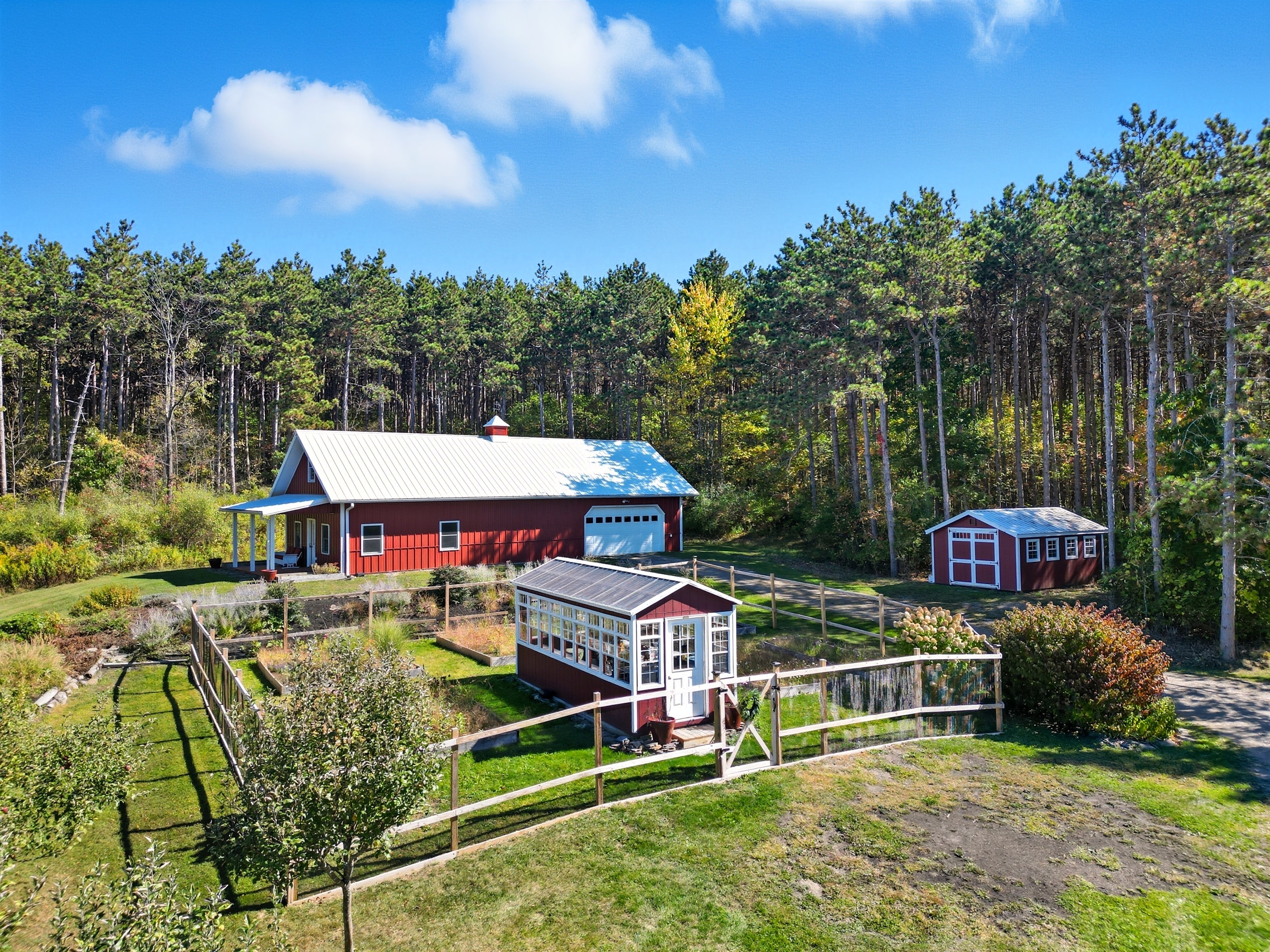 Charming countryside setup with a classic red barn, garden space, and outbuildings—perfect for hobby farming or a serene retreat.