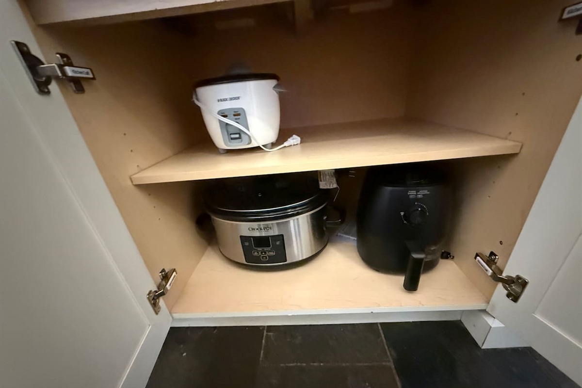 Small Appliance Nook: Convenient cabinet storage houses essential small appliances including a slow cooker, rice cooker and air fryer.  