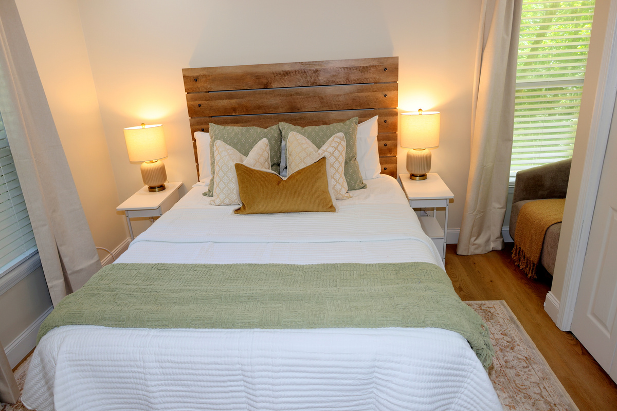Warm and inviting bedroom with wood headboard, layered pillows, and cozy bedding