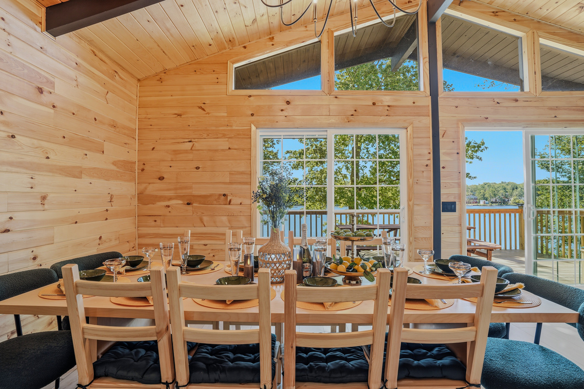 Dining area set for the group — seating for 12 with lake views and vaulted ceiling overhead