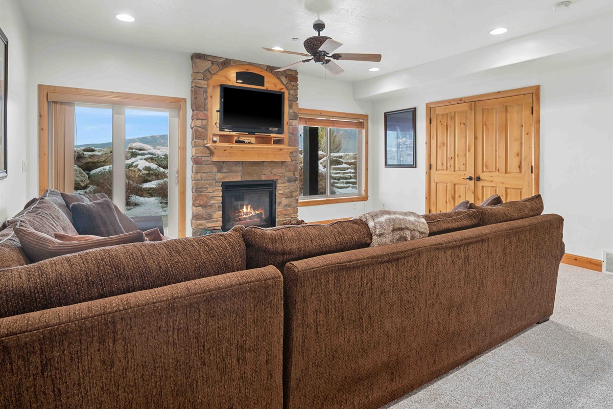 An inviting living space with a fireplace and scenic outdoor views. Note that the Murphy bed is in the closet. Access to the patio and stair access to the large grass lawn.