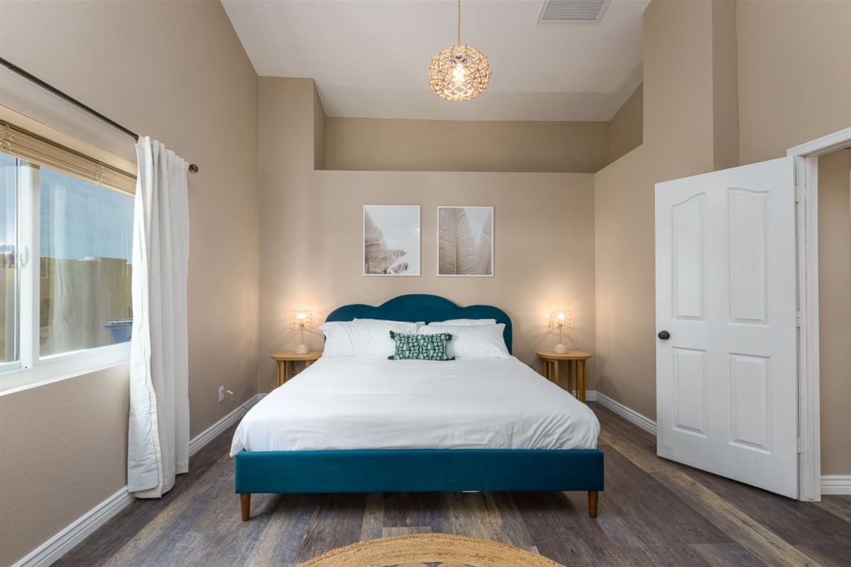 Spacious master bedroom with king bed, high ceilings, and soft bedding for a relaxed stay.