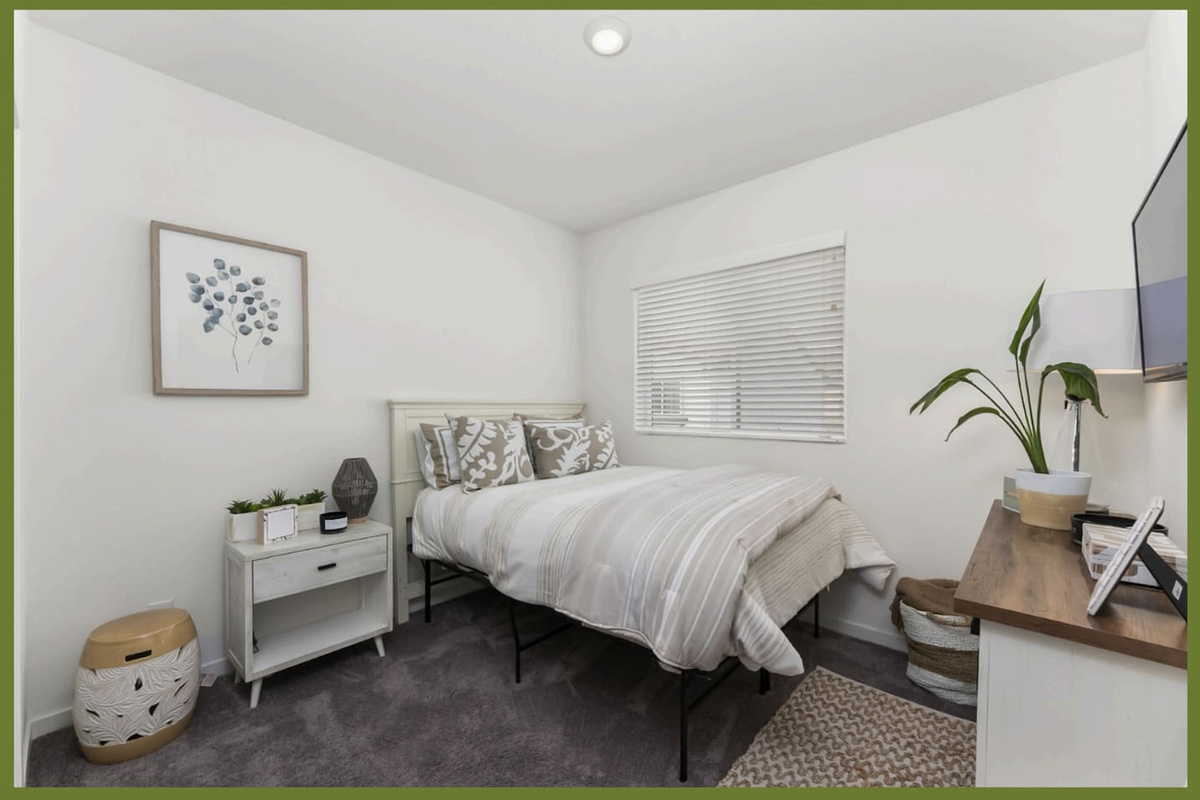 Guest bedroom with a comfortable queen bed, wall-mounted TV, nightstand, and a clean setup for a restful stay.